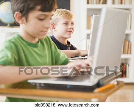 Stock Photo - Boys using laptops in classroom. Fotosearch