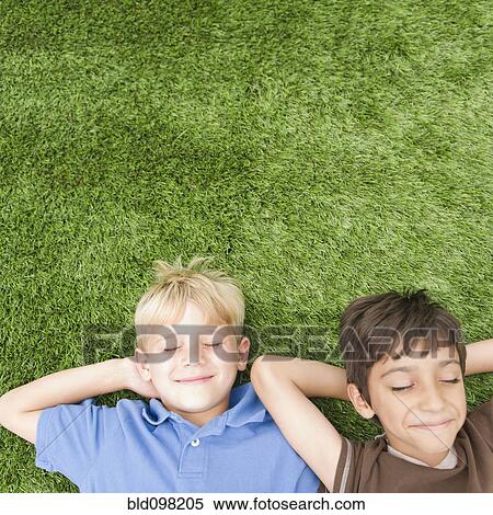 Stock Photography - Boys with eyes closed laying in grass. Fotosearch