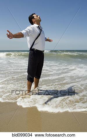 Picture - Businessman wading in ocean. Fotosearch