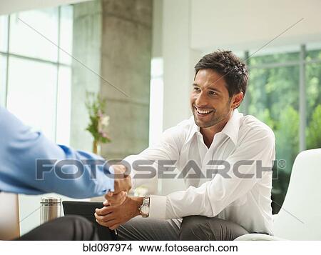 Picture - Businessmen shaking hands in lobby. Fotosearch
