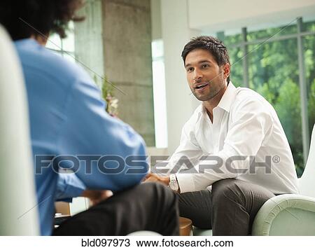 Stock Image - Businessmen talking together in lobby. Fotosearch
