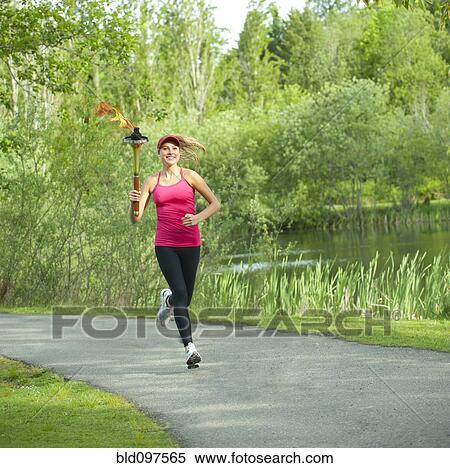 Caucasian athlete running with Olympic torch on park path View Large Photo Image Stock Photography - Caucasian athlete running with Olympic torch on park path. Fotosearch