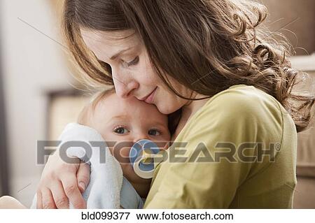 Stock Photo - Caucasian baby boy with pacifier in mother's arms. Fotosearch