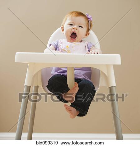 Stock Photo - Caucasian baby girl yawning in high chair. Fotosearch