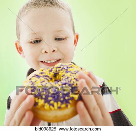 Stock Photography - Caucasian boy eating donut. Fotosearch