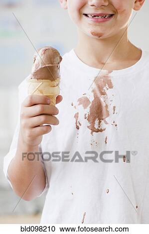 Stock Image - Caucasian boy eating dripping ice cream cone. Fotosearch