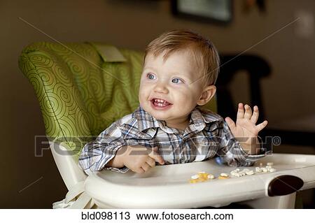 Stock Image - Caucasian boy eating in high chair. Fotosearch