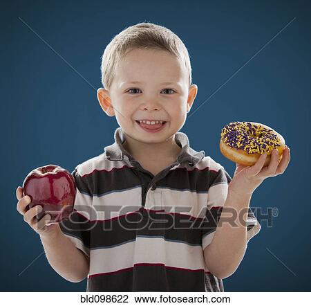 Caucasian boy holding apple and donut View Large Photo Image Stock Image - Caucasian boy holding apple and donut. Fotosearch