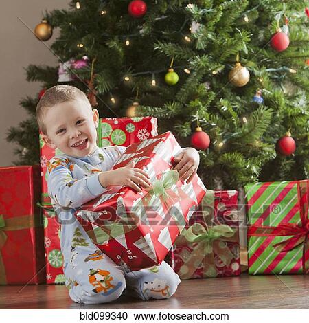 Stock Image - Caucasian boy holding Christmas gift. Fotosearch