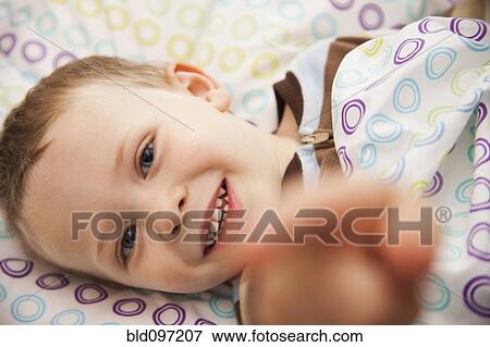 Stock Photo - Caucasian boy laying in bed. Fotosearch
