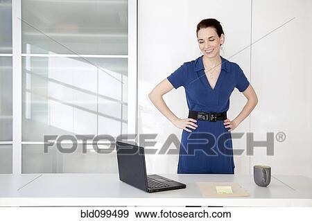 Stock Photo - Caucasian businesswoman standing near desk. Fotosearch