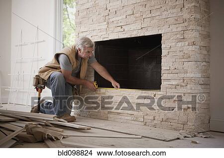 Picture - Caucasian carpenter measuring fireplace. Fotosearch