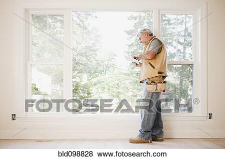 Stock Photo - Caucasian carpenter using digital tablet in empty room. Fotosearch