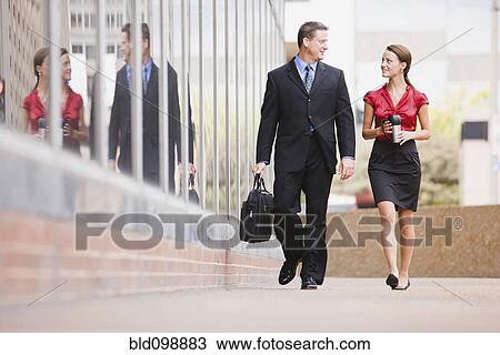 Stock Image - Caucasian co-workers walking together outdoors. Fotosearch
