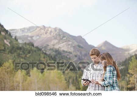 Stock Photograph - Caucasian couple looking at GPS device in remote area. Fotosearch