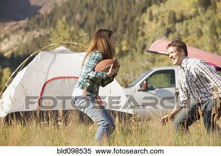 Stock Photography - Caucasian couple playing football at campsite. Fotosearch