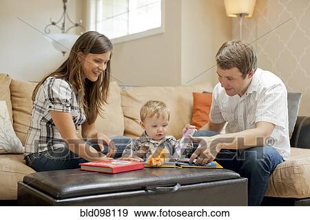 Stock Photo - Caucasian couple playing with son in living room. Fotosearch
