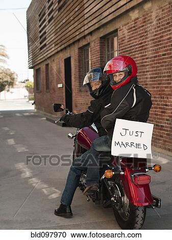Stock Image - Caucasian couple riding on motorcycle with Just Married sign. Fotosearch
