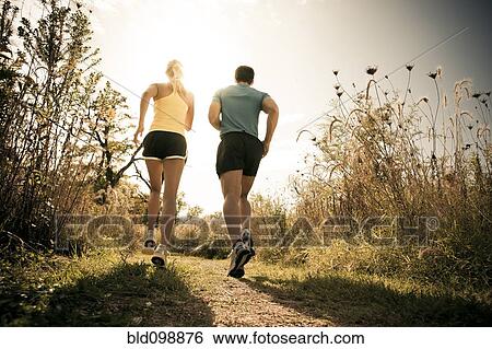 Stock Photograph - Caucasian couple running together on path. Fotosearch