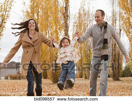 Stock Photo - Caucasian family playing in autumn leaves. Fotosearch
