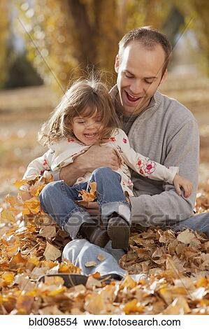 Picture - Caucasian father and daughter playing in autumn leaves. Fotosearch