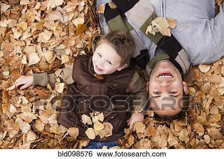 Caucasian father and son laying in autumn leaves View Large Photo Image Stock Photograph - Caucasian father and son laying in autumn leaves. Fotosearch