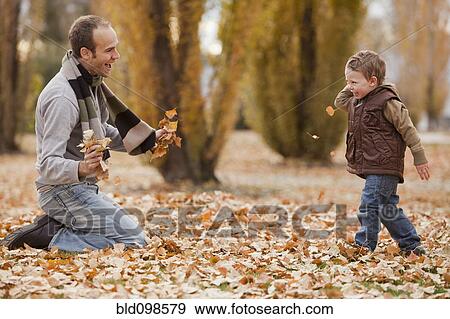 Caucasian father and son playing in autumn leaves View Large Photo Image Stock Photo - Caucasian father and son playing in autumn leaves. Fotosearch