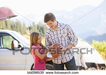 Caucasian father teaching daughter to play football View Large Photo Image Stock Photo - Caucasian father teaching daughter to play football. Fotosearch