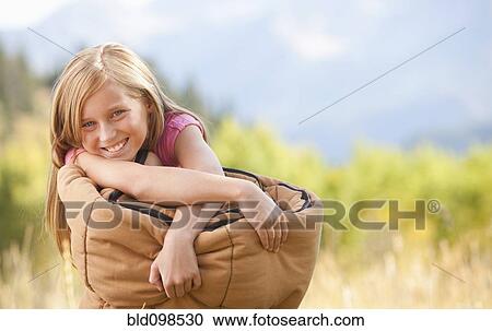 Stock Image - Caucasian girl holding sleeping bag. Fotosearch