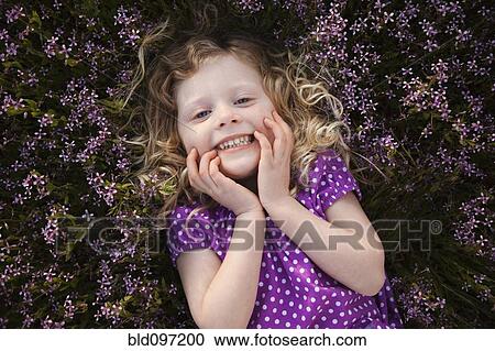 Stock Image - Caucasian girl laying in flowers. Fotosearch