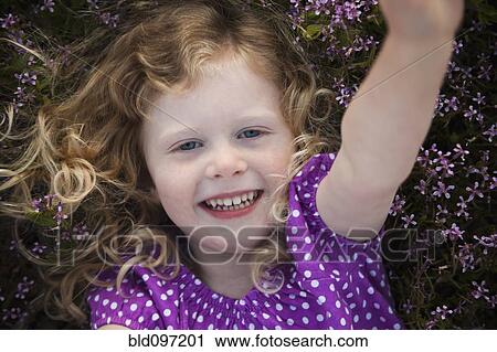 Stock Image - Caucasian girl laying in flowers. Fotosearch