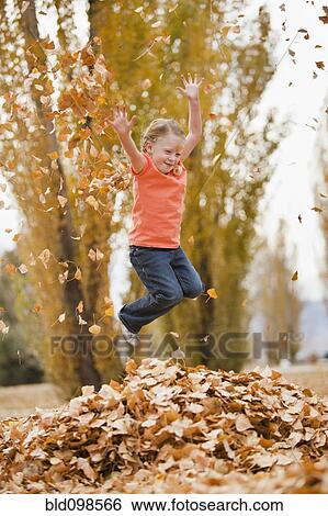 Stock Photograph - Caucasian girl playing in autumn leaves. Fotosearch