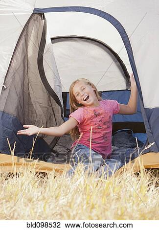 Stock Image - Caucasian girl sitting in tent. Fotosearch