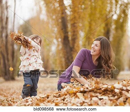 Caucasian girl throwing autumn leaves at mother View Large Photo Image Stock Photo - Caucasian girl throwing autumn leaves at mother. Fotosearch