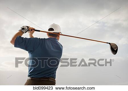 Stock Image - Caucasian golfer swinging golf club. Fotosearch