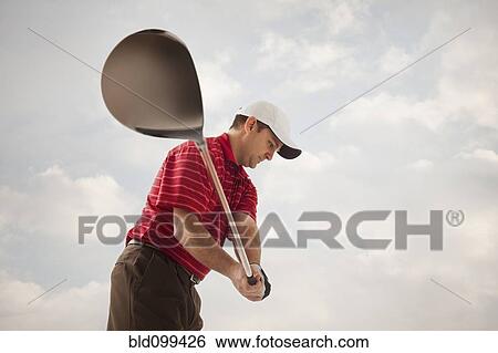 Stock Photograph - Caucasian golfer swinging golf club. Fotosearch