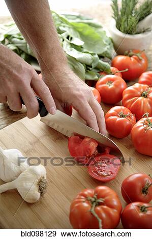 Stock Photo - Caucasian man chopping tomatoes. Fotosearch