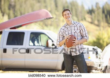 Stock Image - Caucasian man holding football. Fotosearch