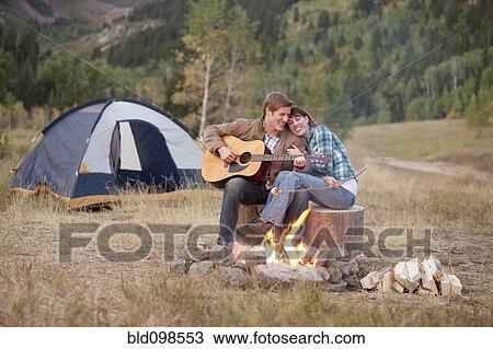 Caucasian man playing guitar for wife near campfire View Large Photo Image Stock Image - Caucasian man playing guitar for wife near campfire. Fotosearch