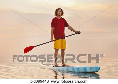 Caucasian man standing on paddle board View Large Photo Image Stock Image - Caucasian man standing on paddle board. Fotosearch
