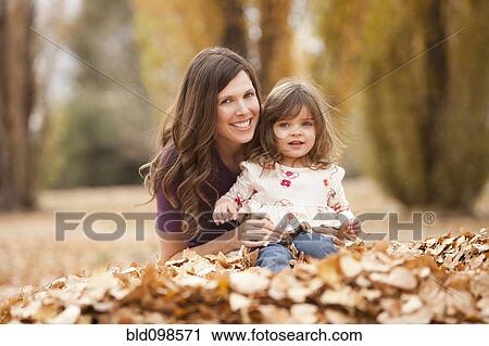 Caucasian mother and daughter playing in autumn leaves View Large Photo Image Stock Image - Caucasian mother and daughter playing in autumn leaves. Fotosearch