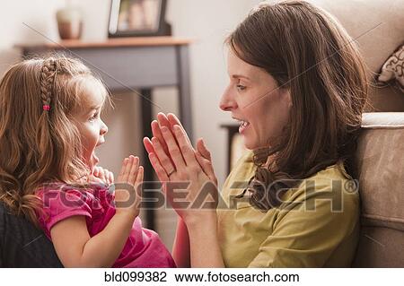 Stock Image - Caucasian mother and daughter playing clapping game. Fotosearch