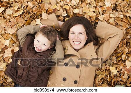 Picture - Caucasian mother and son laying autumn leaves. Fotosearch