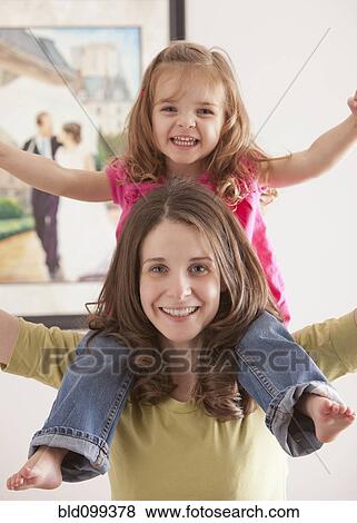 Stock Photo - Caucasian mother carrying daughter on her shoulders. Fotosearch