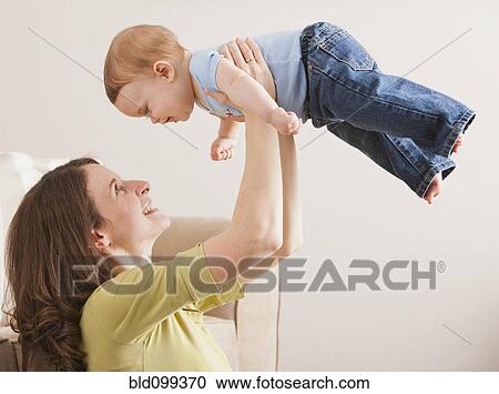 Stock Image - Caucasian mother lifting son in the air. Fotosearch