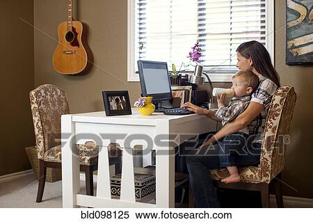Stock Photography - Caucasian mother using computer with son on lap. Fotosearch