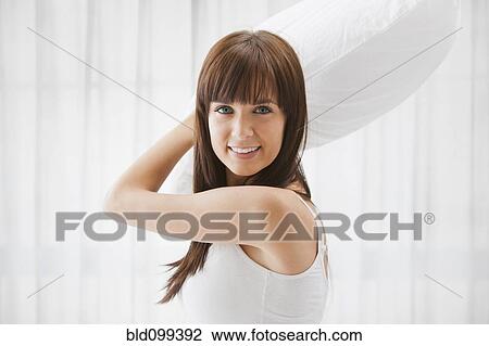 Stock Image - Caucasian woman about to throw pillow. Fotosearch