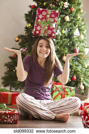 Stock Image - Caucasian woman balancing Christmas gift on her head. Fotosearch