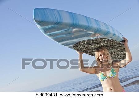 Caucasian woman carrying paddle board View Large Photo Image Stock Image - Caucasian woman carrying paddle board. Fotosearch