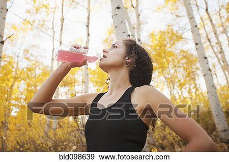 Stock Photo - Caucasian woman drinking juice after exercise. Fotosearch